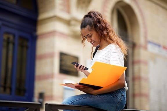 female college student with books and mobile phone