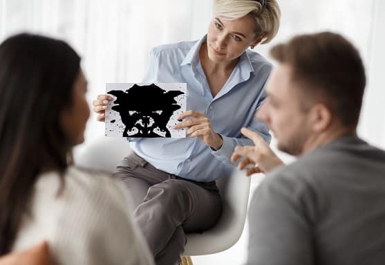 psychologist testing couple showing inkblot picture sitting in office