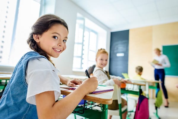 little schoolgirls looking at camera during lesson at school