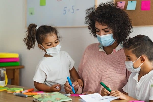 teacher with children wearing face mask in preschool classroom d