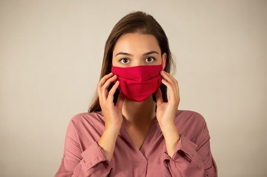 young woman touching red mask on the face in studio