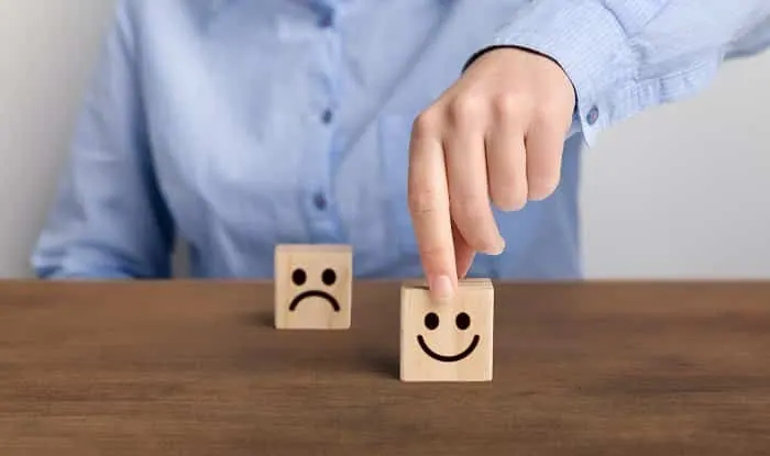 hand of a businessman chooses a smiley face on wood block cube