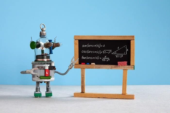 artificial intelligence and trigonometry lesson in college. robot teacher explains theory inverse trigonometric functions. classroom interior with handwritten formula black chalkboard. blue gray colorful background