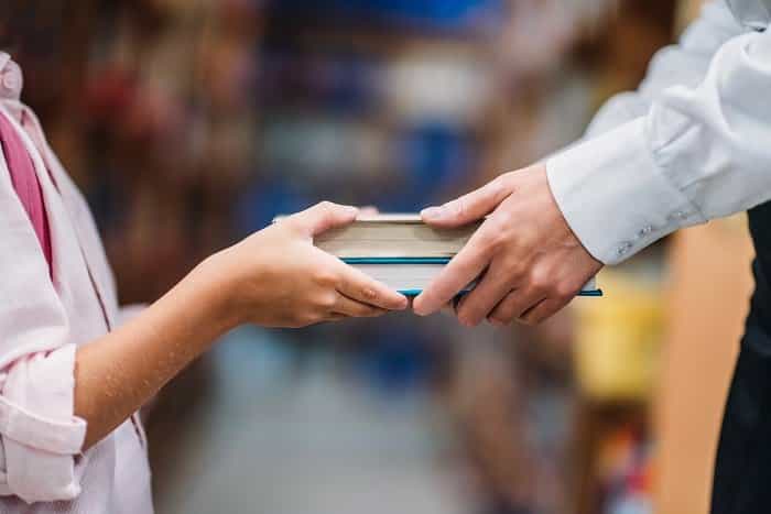 cropped shot of teacher giving books to child