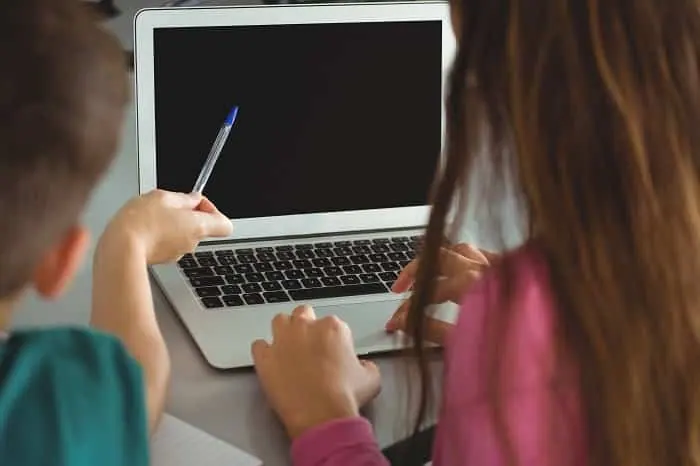 school kids using laptop in library