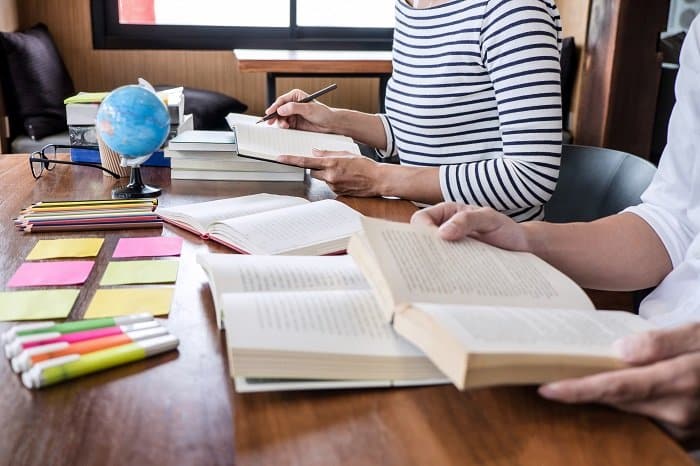 high school or college student group sitting at desk in library