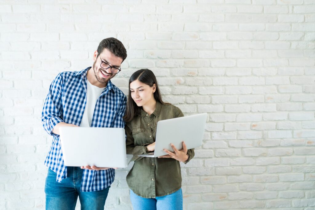 colleagues looking at laptops against wall in office