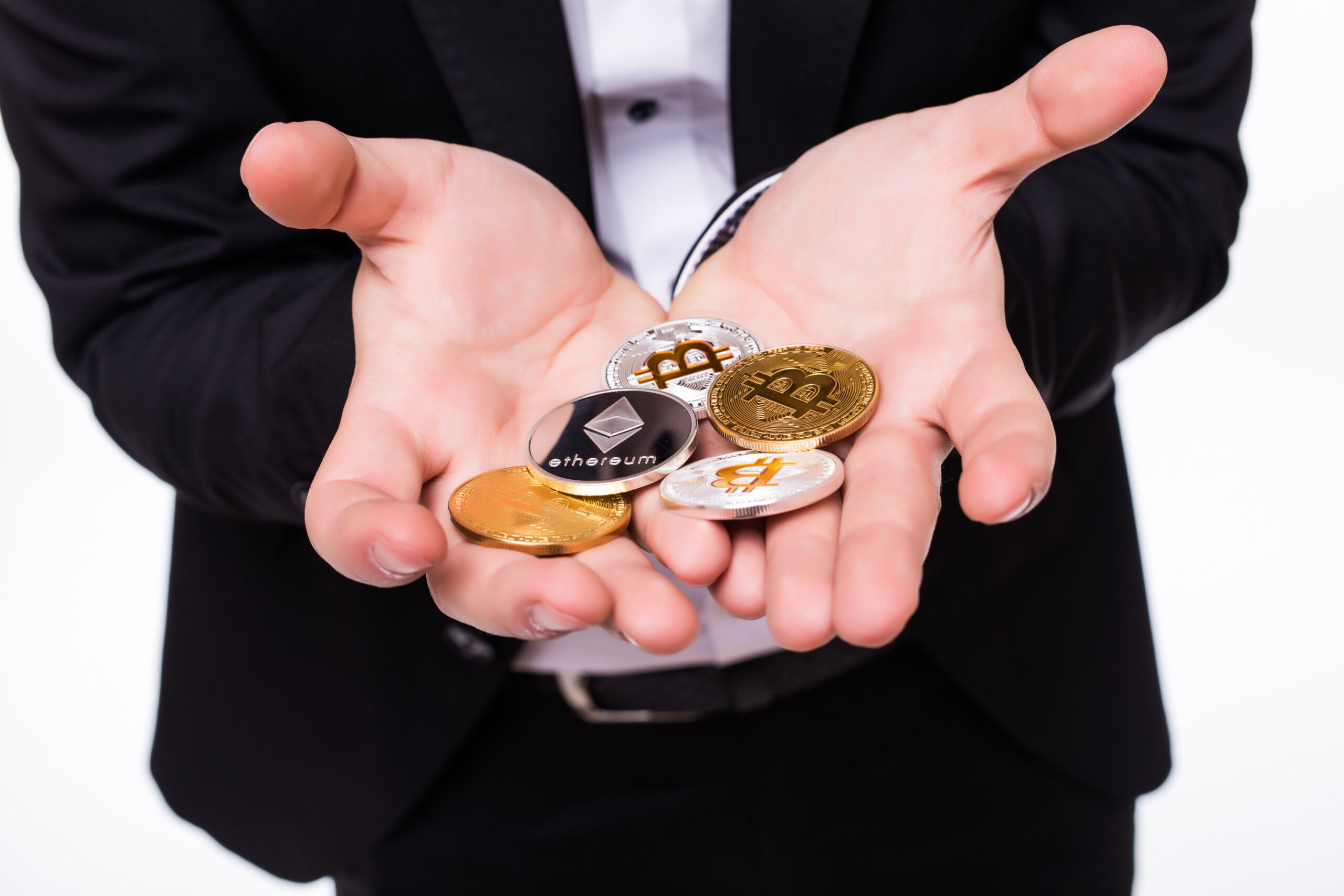 man holds different crypto coins in his hands isolated on white
